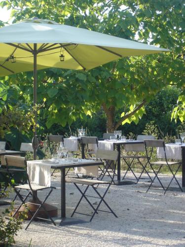 a group of tables and chairs under a yellow umbrella at Hotel La Bastie d'Urfé in Naussac