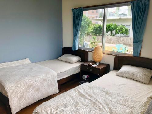 a room with two beds and a window at Life is a Journey in Yomitan