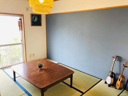 a living room with a wooden table in the corner at Life is a Journey in Yomitan