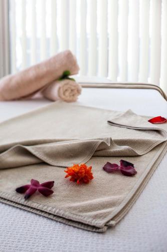 a tray with a napkin with flowers on a bed at Tusan Beach Resort - All Inclusive in Kuşadası