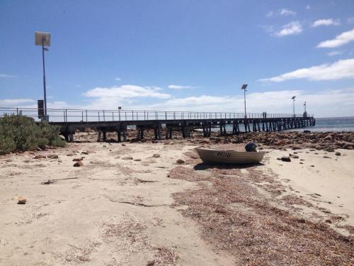 a boat sitting on the beach near a pier at Pine View Holiday Rental in Emu Bay