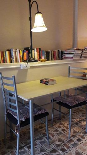 a table with two chairs and a shelf with books at Chomhaad Guesthouse in Hua Hin