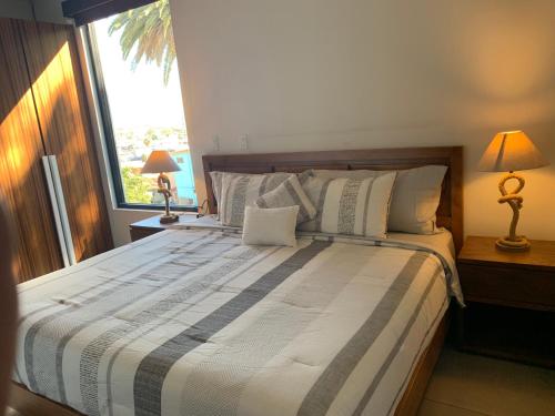 a bedroom with a large bed with two lamps and a window at El Refugio in Ensenada