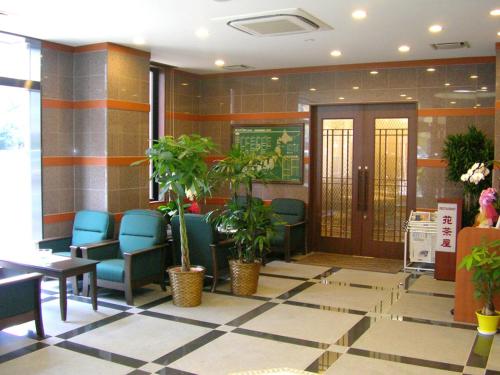 a waiting area with chairs and plants in a building at Hotel Route-Inn Oita Ekimae in Oita
