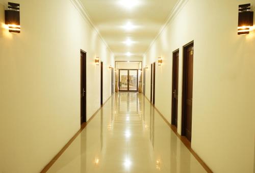 a corridor of a building with white walls and doors at RedDoorz Syariah At Namira Hotel in Yogyakarta