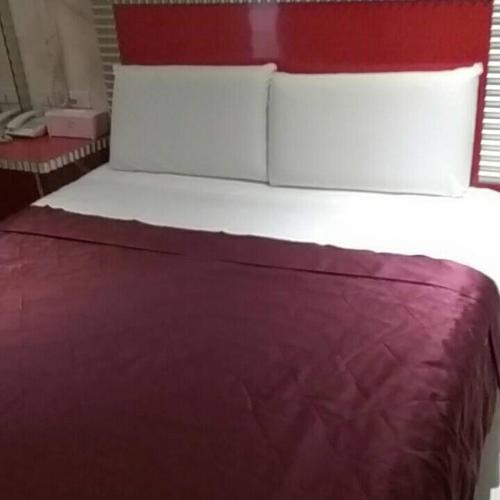 a red bed with two pillows on top of it at Meets Happy Hotel in Yonghe