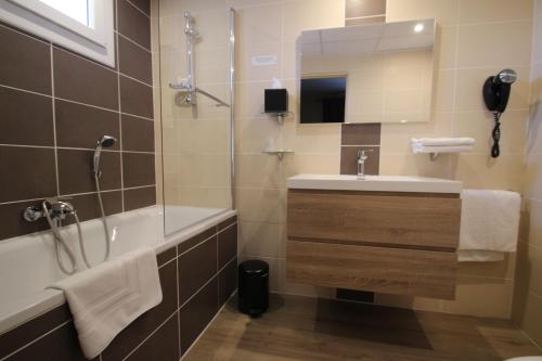 La salle de bains est pourvue d'une baignoire, d'un lavabo et d'une douche. dans l'établissement Hôtel Le Valaurie, à Saint-Nazaire