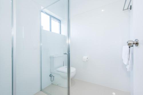 a bathroom with a toilet and a glass shower at Casa Nostra Motel Mackay in Mackay