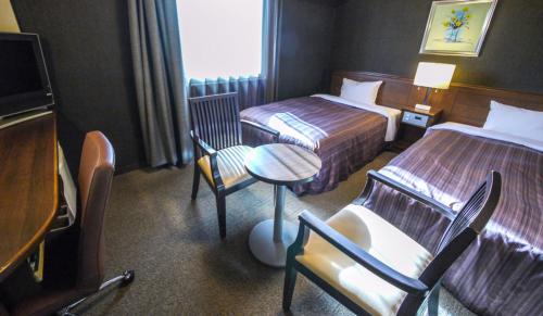 一関市にあるホテルルートイン　一関インターのベッド2台、テーブルと椅子が備わるホテルルームです。