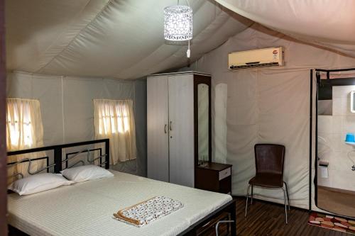 a bedroom with a bed and a chair in a tent at Tent-O-Treat Premium Rooms near Dapoli in Dapoli