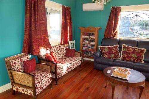 a living room with a couch and chairs and a table at Fantail Cottage in Oamaru