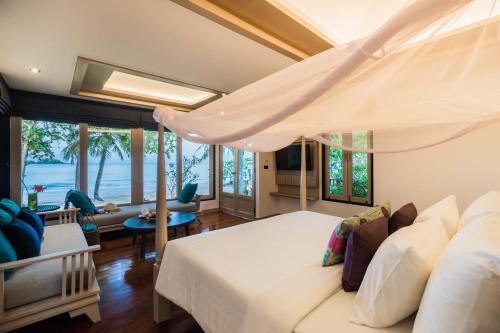 ein Schlafzimmer mit einem Bett und ein Wohnzimmer in der Unterkunft Barali Beach Resort & Spa in Ko Chang