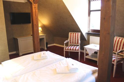 a bedroom with a bed and two chairs and a television at Schlosshotel Stecklenberg in Thale
