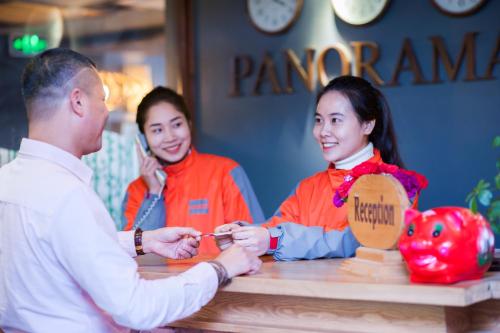 un hombre entregando comida a una chica en una mesa en Sapa Panorama Hotel, en Sa Pa