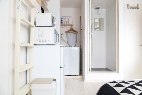 a small kitchen with a refrigerator and a microwave at Cozy Vibes Apt Hotel in Tokyo