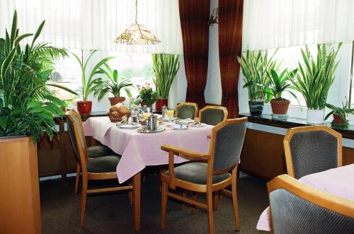 a dining room with a table and chairs and plants at Hotel Delfthalle in Emden