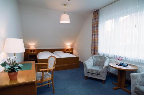 une chambre d'hôtel avec un lit, une table et des chaises dans l'établissement Hotel Delfthalle, à Emden