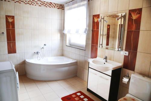 a bathroom with a tub and a sink at Willa Mona in Międzywodzie