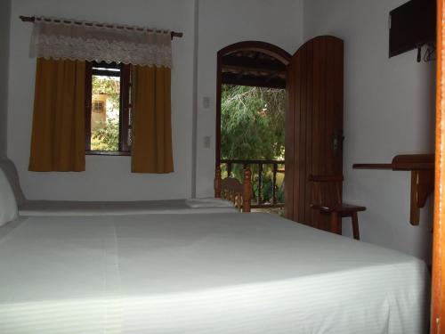 um quarto com uma cama branca e 2 janelas em Pousada Flats Paguru em Búzios