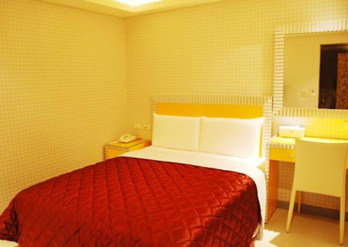 Schlafzimmer mit einem roten Bett und einem Schreibtisch in der Unterkunft Meets Happy Hotel in Yonghe