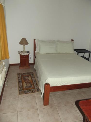 a bedroom with a bed and a lamp on a table at Pousada Flats Paguru in Búzios