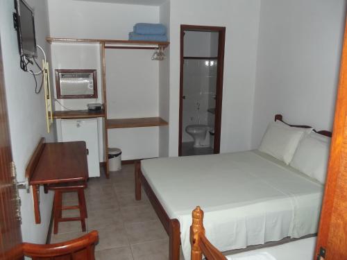 a bedroom with a bed and a table and a desk at Pousada Flats Paguru in Búzios