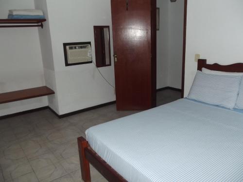 a bedroom with a bed in a room with a door at Pousada Flats Paguru in Búzios