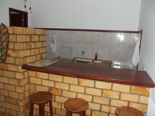a kitchen with two stools and a brick wall at Pousada Flats Paguru in Búzios
