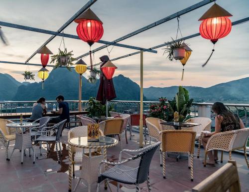 a patio with tables and chairs with mountains in the background at Thuong Hai Hotel in Phong Nha