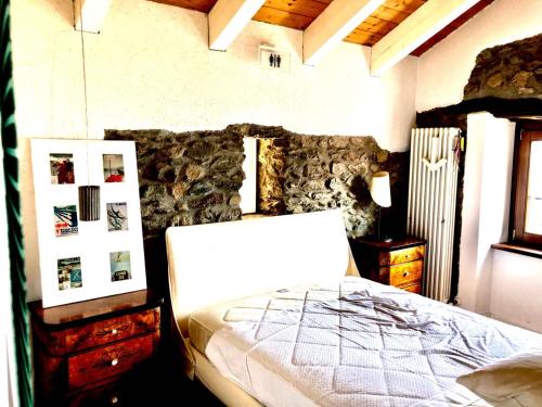 um quarto com uma cama e uma parede de pedra em Casa Della Lavanda em Stazzona