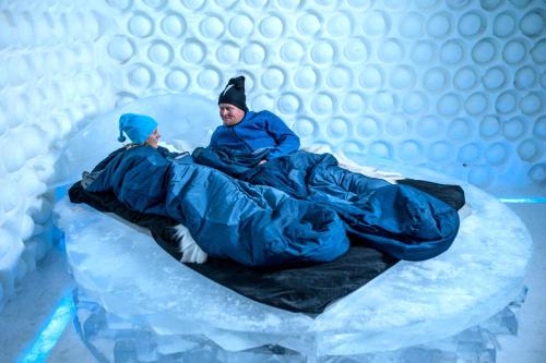 two people laying on a bed in an igloo at IceHotel in Jukkasjärvi