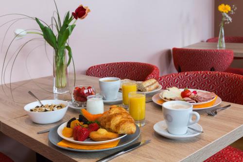 a table topped with plates of breakfast foods and drinks at The Originals Boutique, Hôtel Alizé, Évian-les-Bains in Évian-les-Bains