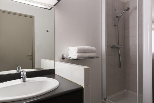 uma casa de banho com um lavatório e um chuveiro em The Originals Boutique, Hôtel Alizé, Évian-les-Bains (Inter-Hotel) em Évian-les-Bains