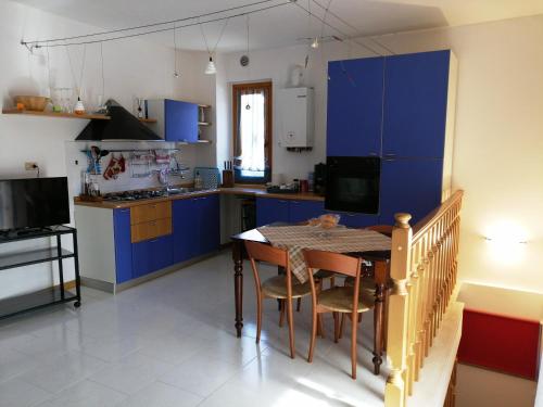 uma cozinha com armários azuis e uma mesa com cadeiras em A casa di Vince Monteaperti em Montaperti