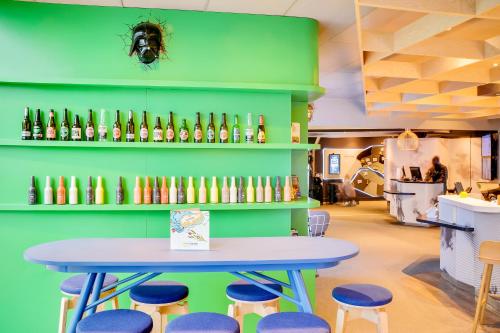 a table and stools in a room with bottles on the wall at ibis Styles Paris Charles de Gaulle Airport in Roissy-en-France
