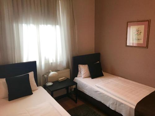two beds in a small room with a window at Waldhotel "Peter aufm Berge" in Bielefeld