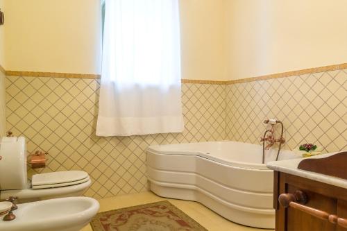 een badkamer met een bad, een toilet en een wastafel bij Dimora Cariga - Home & pool in Giarre