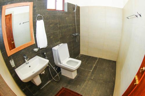 a bathroom with a sink and a toilet and a mirror at Bay Hiriketiya in Hiriketiya