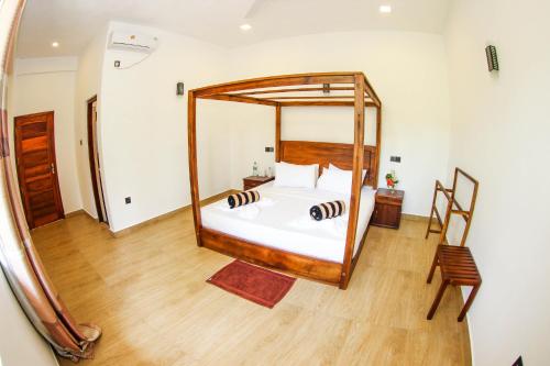 a bedroom with a large bed with a wooden frame at Bay Hiriketiya in Hiriketiya