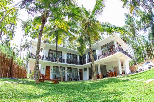 una gran casa blanca con palmeras delante en Bay Hiriketiya, en Hiriketiya