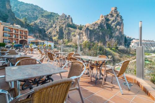 a patio with tables and chairs and a mountain at Hotel Sierra de Cazorla & SPA 3* in Cazorla