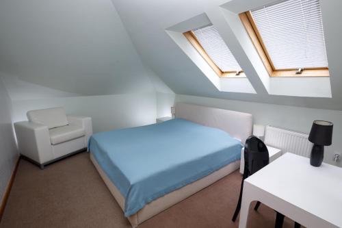 1 dormitorio con 1 cama, 1 silla y 2 ventanas en Art Garni Hotel en Kanjiža