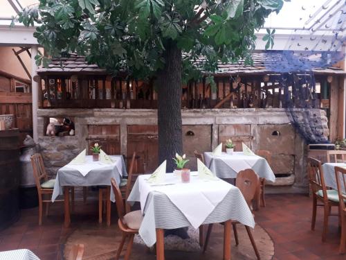 a restaurant with tables with white tablecloths and a tree at Brauereigasthof Dachsenfranz in Zuzenhausen