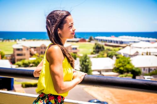 a woman standing on a balcony looking at the ocean at The Lord Forrest Hotel in Bunbury