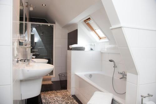 een witte badkamer met een wastafel en een bad bij Boutique B&B de PASTORY in Zuiddorpe