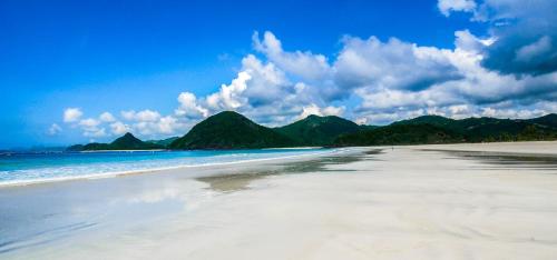 a view of a beach with mountains in the background at Mango Lodge in Selong Belanak