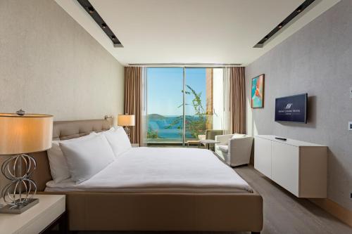 a hotel room with a bed and a large window at Sirene Luxury Hotel Bodrum in Yalıkavak
