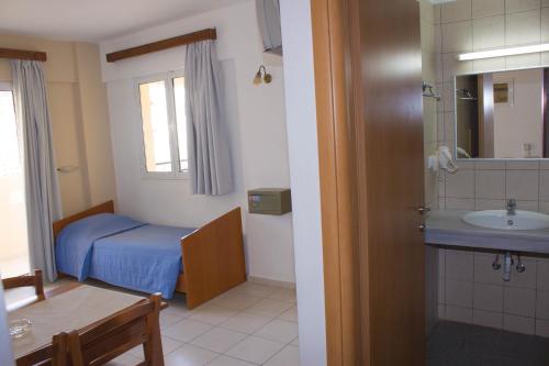 a small bathroom with a bed and a sink at Sunshine Studios & Apartments in Stalís