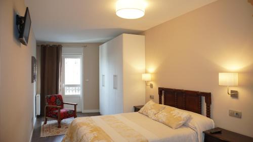 a bedroom with a bed and a chair and a window at Apartamento Vía Romana XIX in Lugo