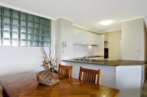 a kitchen and dining room with a wooden table and chairs at San Marino by the Sea Apartments in Marcoola